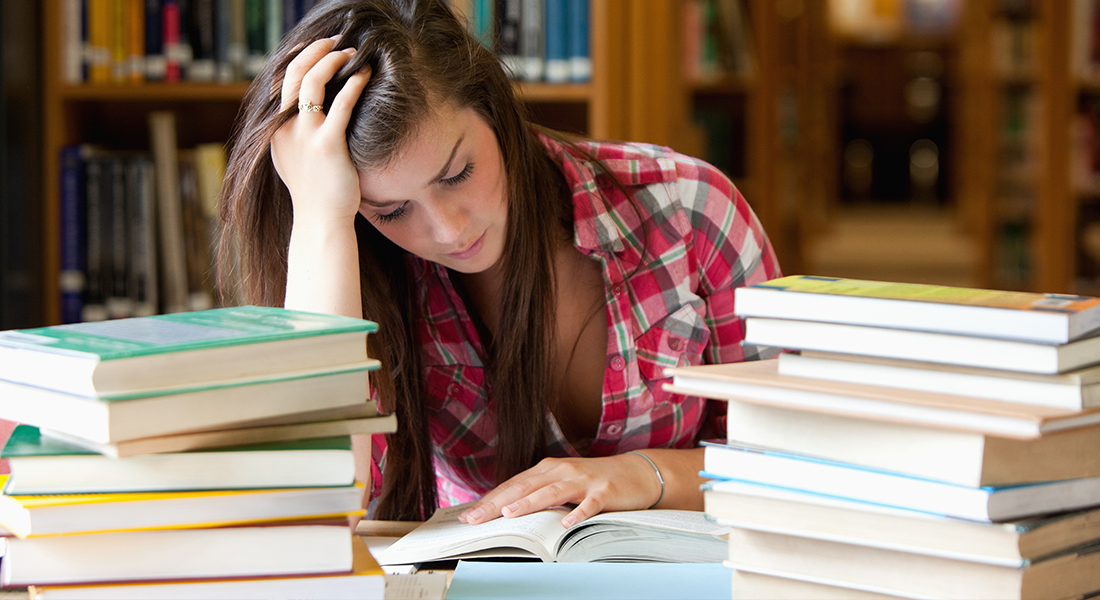 A stressed student surrounded by books and papers, looking worried about upcoming exams